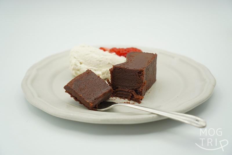 ビーントゥバーチョコレート専門店 Minimal（ミニマル）の生ガトーショコラが生クリームと苺と一緒にさらに載せられ、テーブルに置かれている