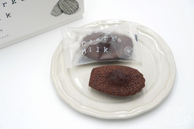 北海道大学の敷地内にある北大マルシェ の「HOKUDAI Clark's Milk マドレーヌ ショコラ」が皿にのせられ、テーブルに置かれている