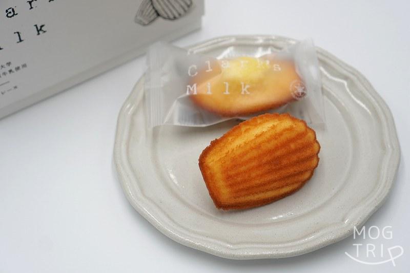 北海道大学の敷地内にある北大マルシェ の「HOKUDAI Clark's Milk マドレーヌ」が皿にのせられ、テーブルに置かれている