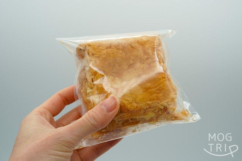 袋に入った倶知安 お菓子のふじいの冷凍カスタードパイを手に持っている様子