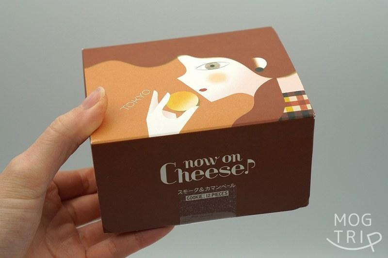 ナウオンチーズの東京駅限定品 スモーク＆カマンベールクッキーの箱を手に持っている様子