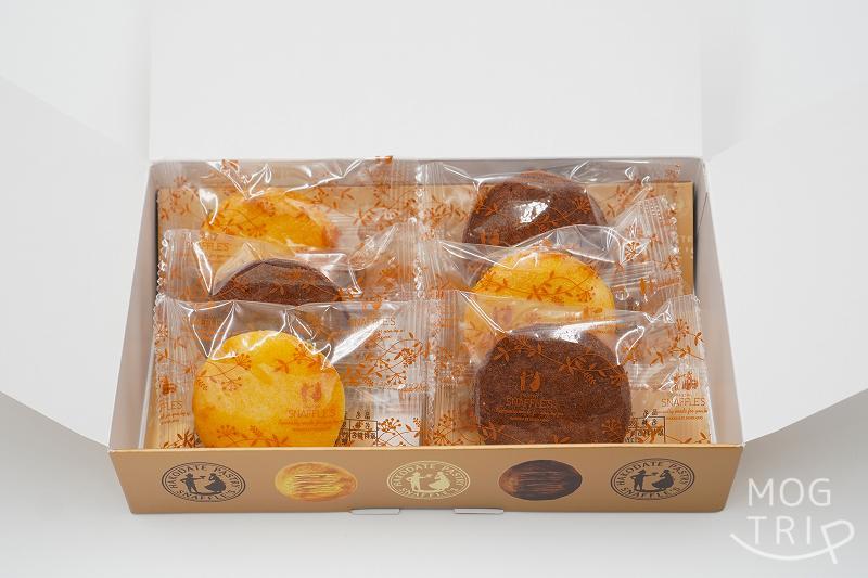 ふたを開けた函館洋菓子スナッフルスの「チッチキー チーズ＆ココア」の箱が、テーブルに置かれている