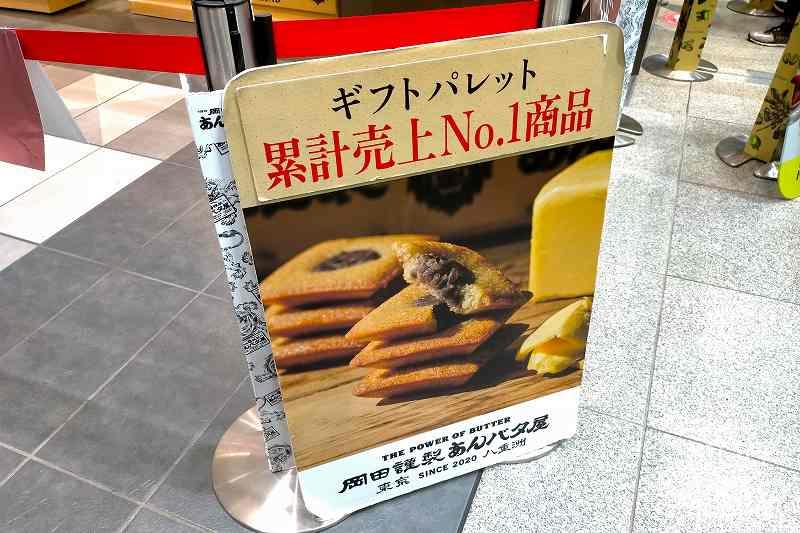 「岡田謹製 あんバタ屋 東京ギフトパレット店」の、あんバタフィナンシェの案内看板が床に置かれている