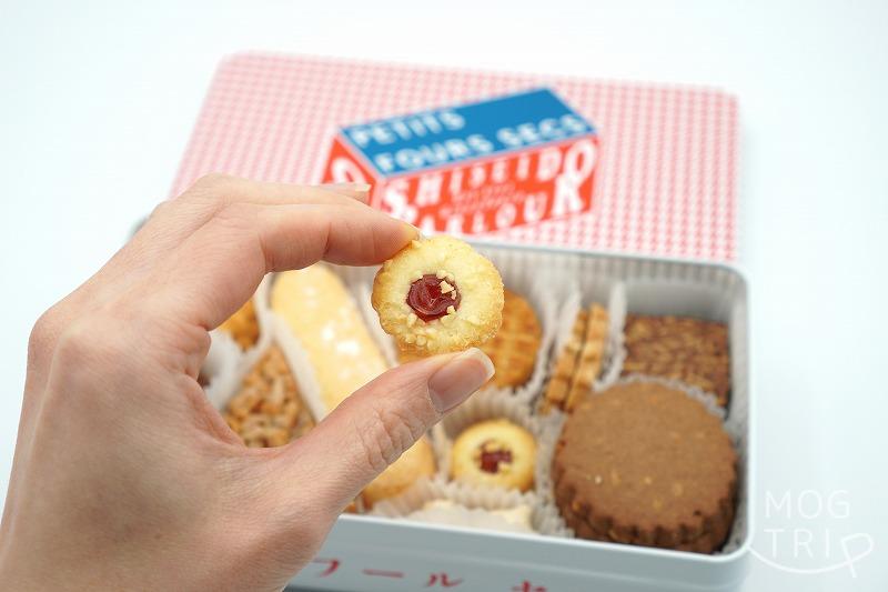 【東京・資生堂パーラー銀座本店限定】クッキー缶・プティフールセック のフランボワーズクッキーを手に持っている様子