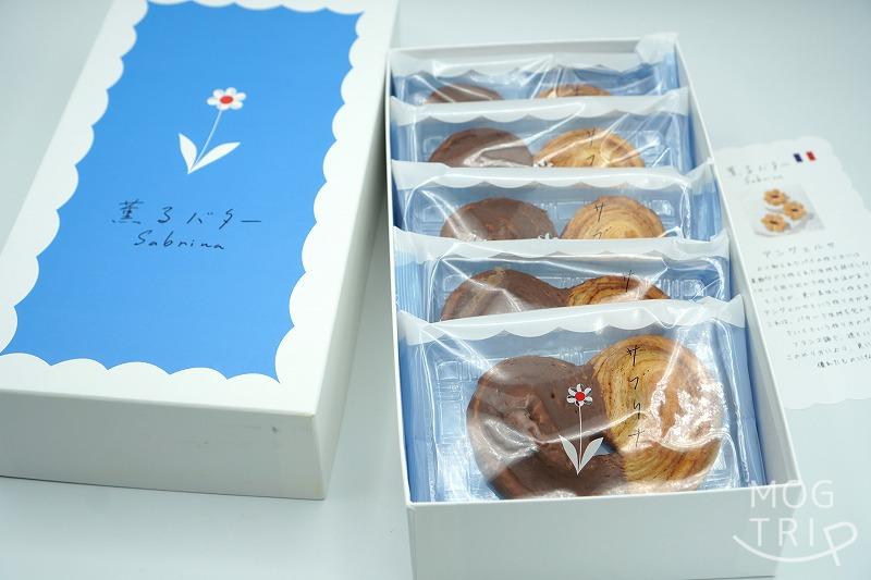 蓋を開けた、東京駅・大阪限定の薫るバターSabrina（サブリナ）の「パルミエ」の箱がテーブルに置かれている