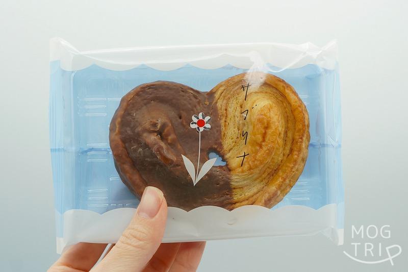 東京駅・大阪限定の薫るバターSabrina（サブリナ）の「パルミエ」の個包装を手に持っている様子