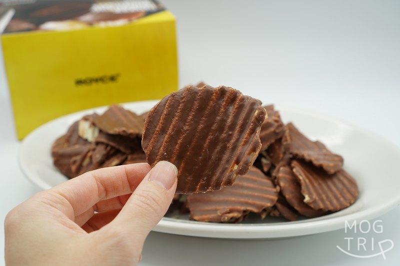 ROYCE’（ロイズ）のポテトチップチョコレートを手に持っている様子