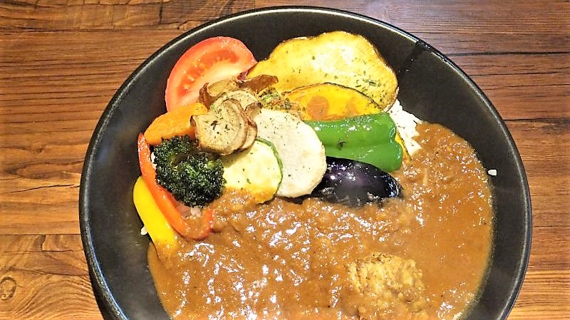 E-itou Curry（エイトカリー）のあべ鶏の煮込みチキンと素揚げ野菜のカレーがテーブルに置かれている