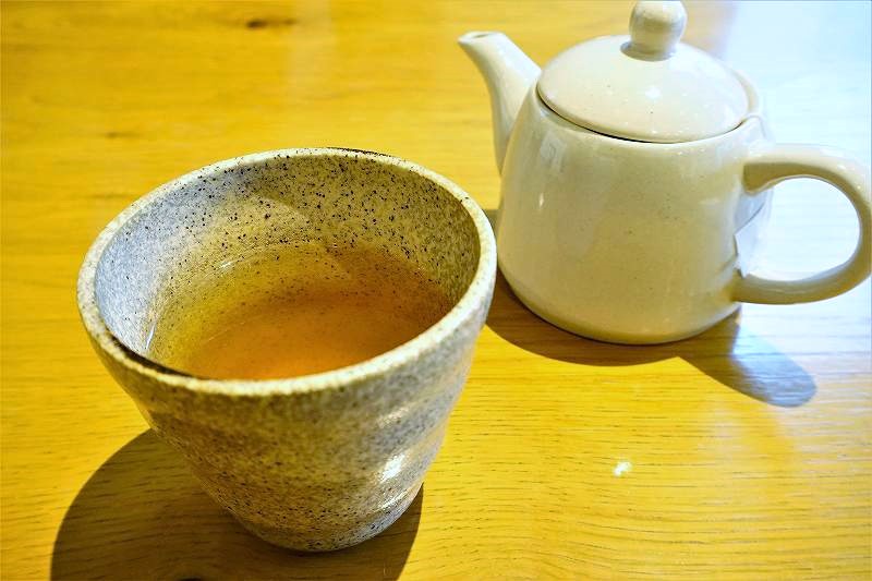 ポットとコップに入ったお茶がテーブルに置かれている
