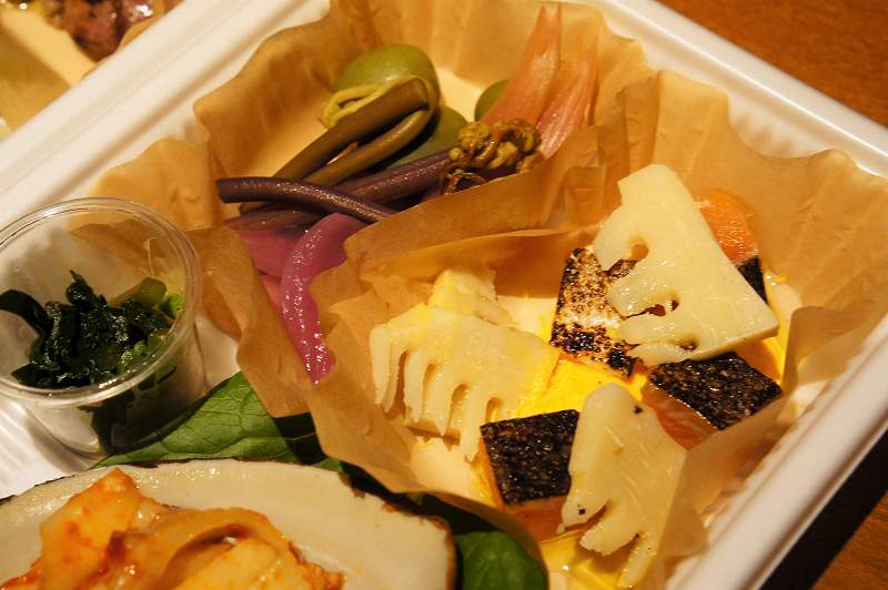 筍、山菜、マスなどを使った前菜がプラスチックケースに入っている