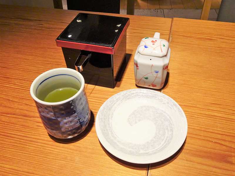 ガリ、醤油、醤油皿、緑茶がテーブルに置かれている