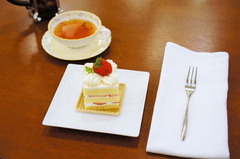苺ショートケーキと紅茶、布ナプキンなどがテーブルに置かれている