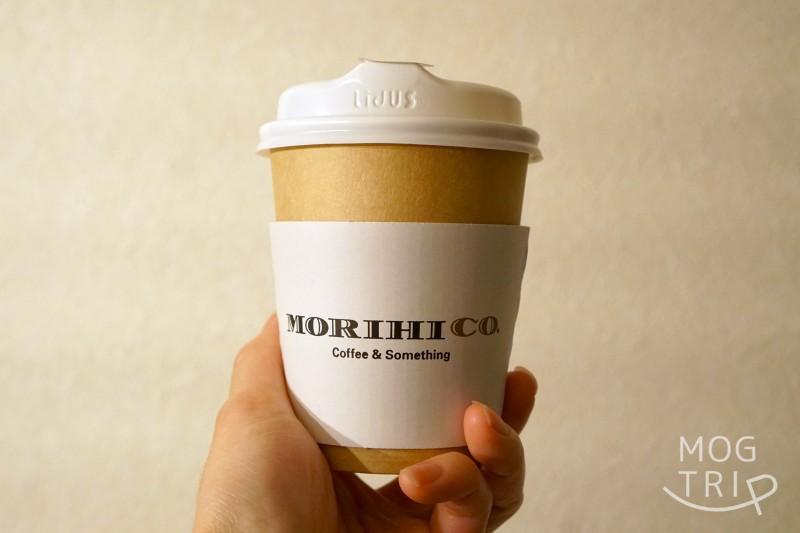 「MORIHICO.STAY&COFFEE（モリヒコ ステイアンドコーヒー）」のコーヒーを手に持っている様子