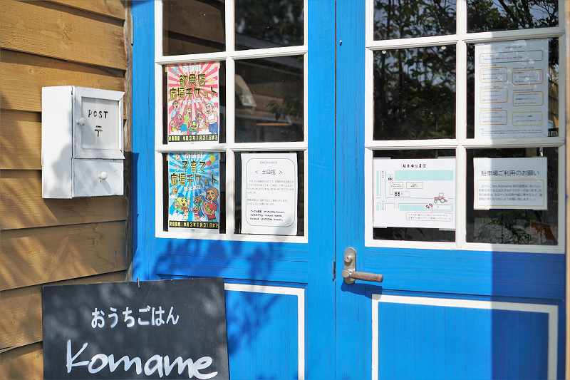 鮮やかなブルーの扉の「おうちごはん Komame（コマメ）」の入口