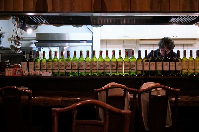 空のワインボトルがずらりと並ぶ「ビストロブランシュ」のカウンター席の様子
