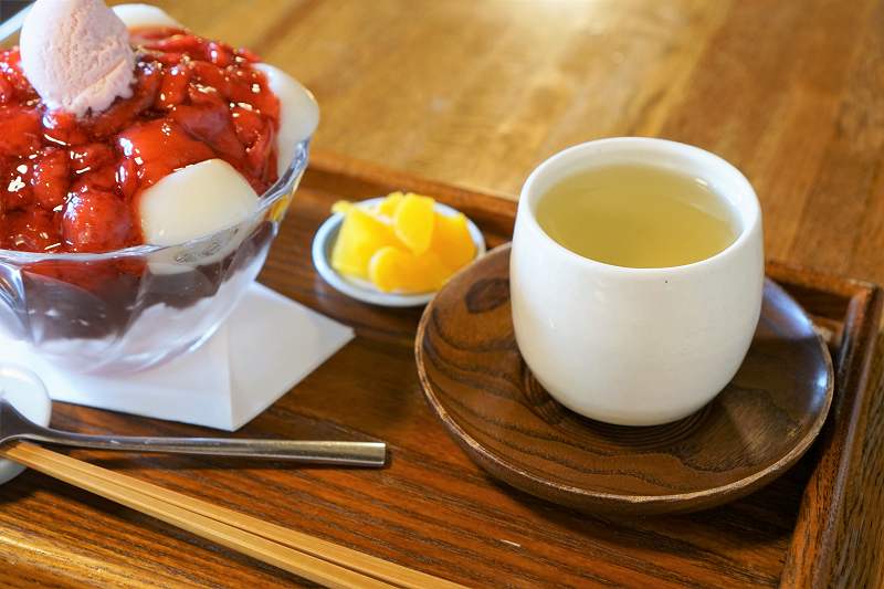 苺ぜんざい白玉入りと日本茶、お漬物がテーブルに置かれている