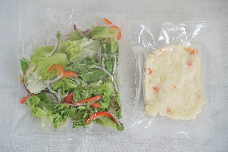 袋に入った生野菜とポテトサラダがテーブルに置かれている