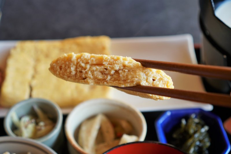  “小樽地鶏卵” の出汁巻玉子を箸で持ち上げている様子