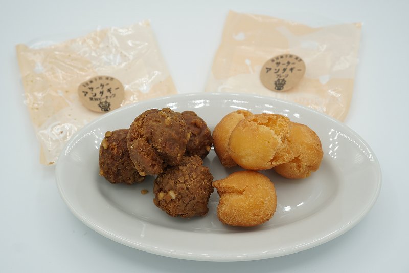 お皿にのせられた沖縄菓子処 琉宮 サーターアンダギーの、黒糖ピーナッツとプレーンがテーブルに置かれている