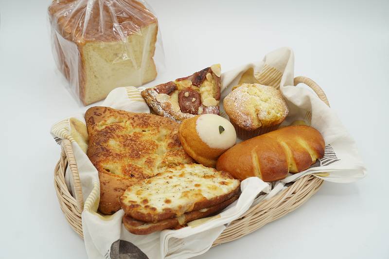 食パンやクリームパンなど「よしぱん」のパンがテーブルに置かれている