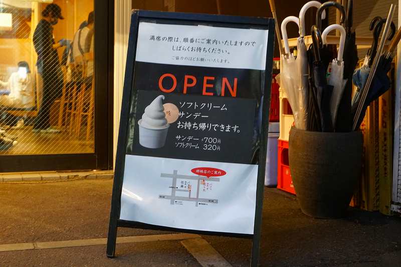 「パフェ、珈琲、酒、佐藤」の店前にサンデーとソフトクリームのテイクアウトメニューが立てられている
