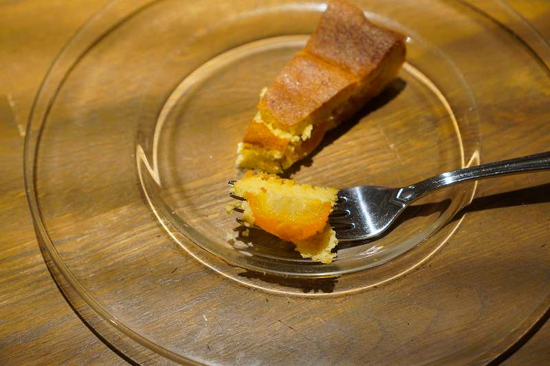 「アーモンドケーキと金柑のコンポート」とフォークがテーブルに置かれている