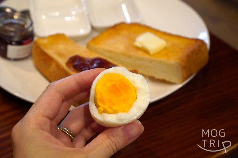 「珈琲亭ちろる」のモーニングセットのゆで卵を手に持っている様子