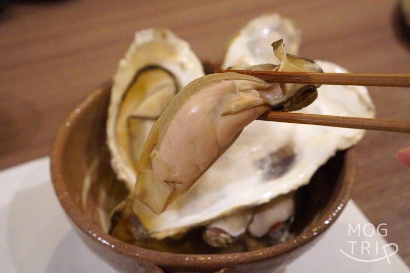 和菜酒房おりべの牡蠣 の酒蒸しを箸で持ち上げている様子