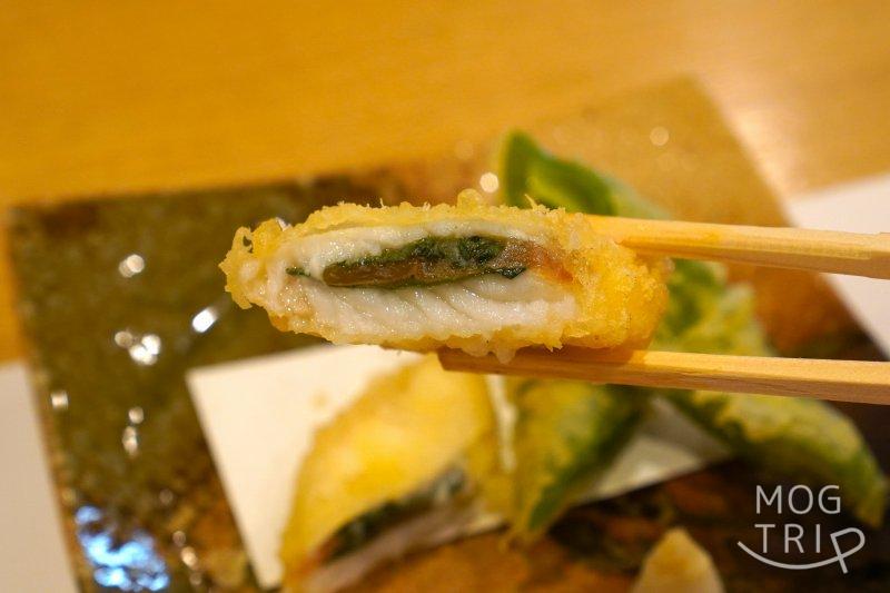 旭川「小西鮨」の羅臼産 銀宝（ギンポ） の天ぷらを箸で持ち上げている様子
