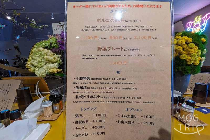 「豚丼ポルコ札幌北13条店」のメニュー表がテーブルに置かれている