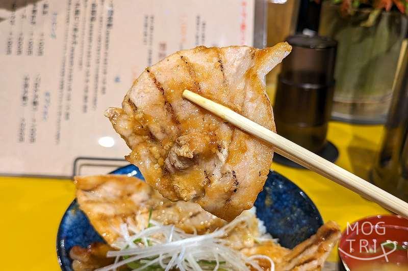 「豚丼ポルコ札幌北13条店」の豚丼札幌ピリ辛みそを箸で持ち上げている様子