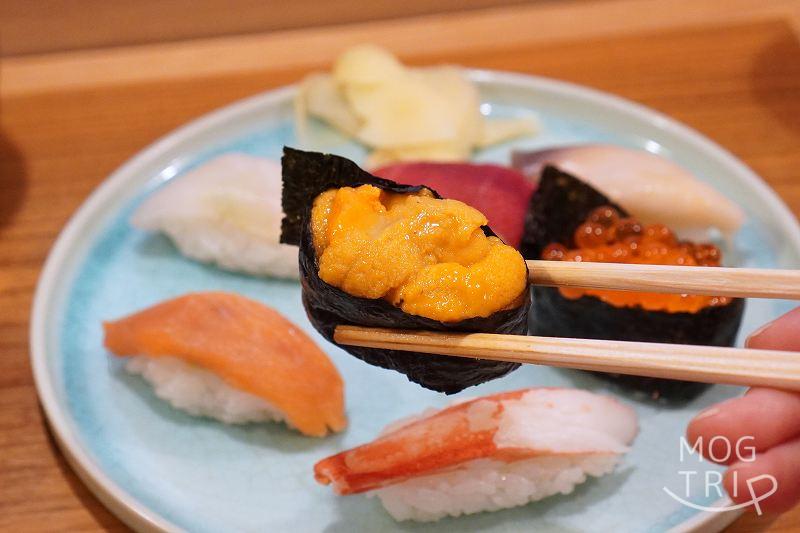 札幌すすきの「鮨処いちい」のうにのお寿司を箸で持ち上げている様子