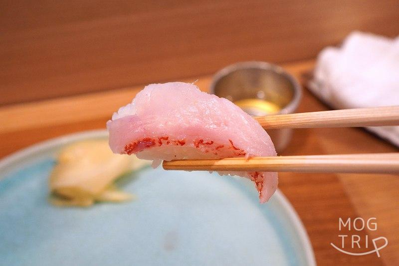 札幌すすきの「鮨処いちい」のきんきの握りを箸で持ち上げている様子