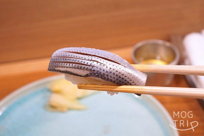 札幌すすきの「鮨処いちい」の小肌の握りを箸で持ち上げている様子