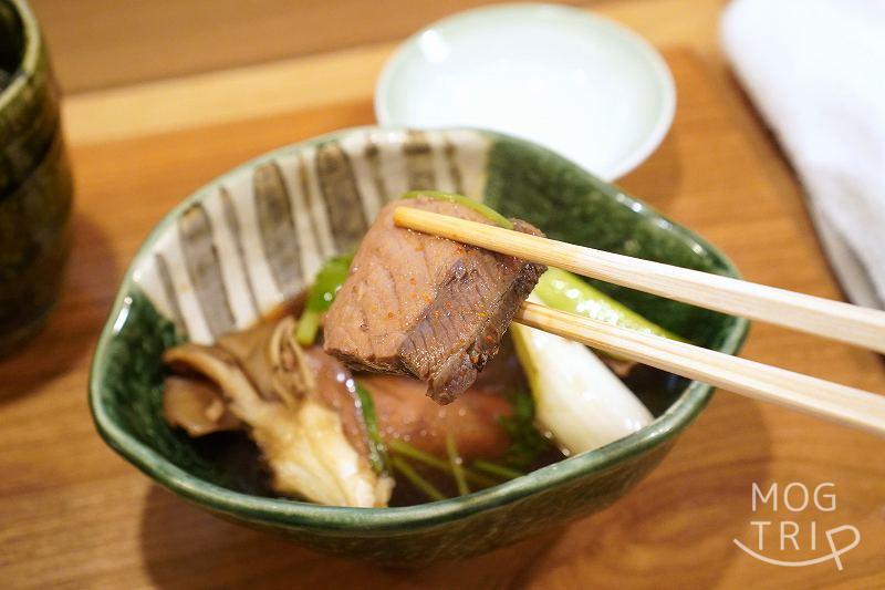 札幌すすきの「鮨処いちい」のカンバチの煮物を箸で持ち上げている様子