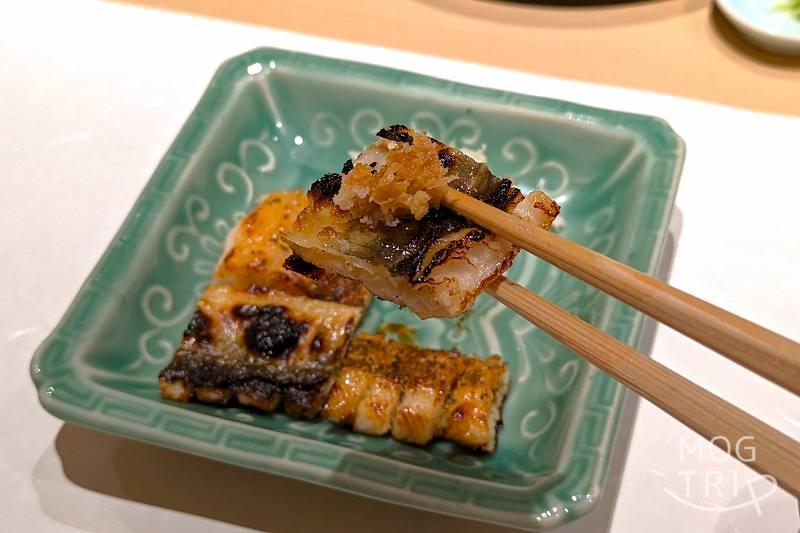 札幌すすきのにある「まる鮨」の穴子のキジ焼きを箸で持ち上げている様子