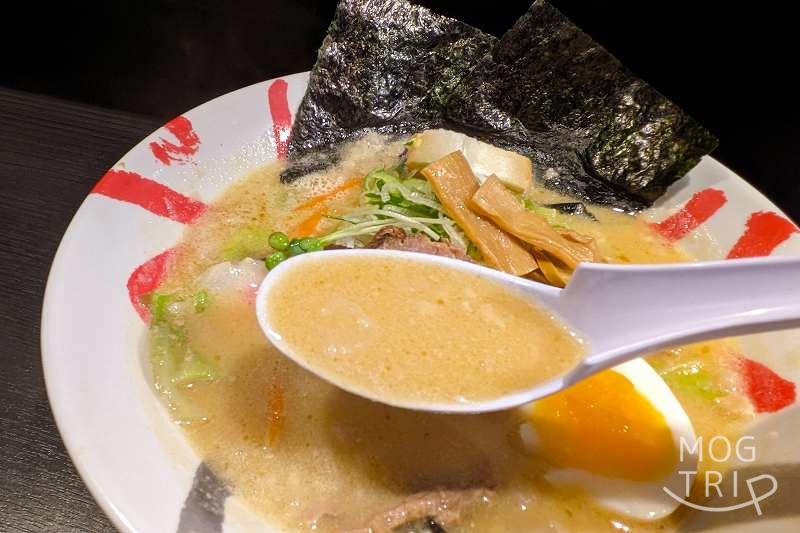「函館麺厨房あじさいモユク札幌店」白味噌ラーメンのスープをレンゲで持ち上げた様子