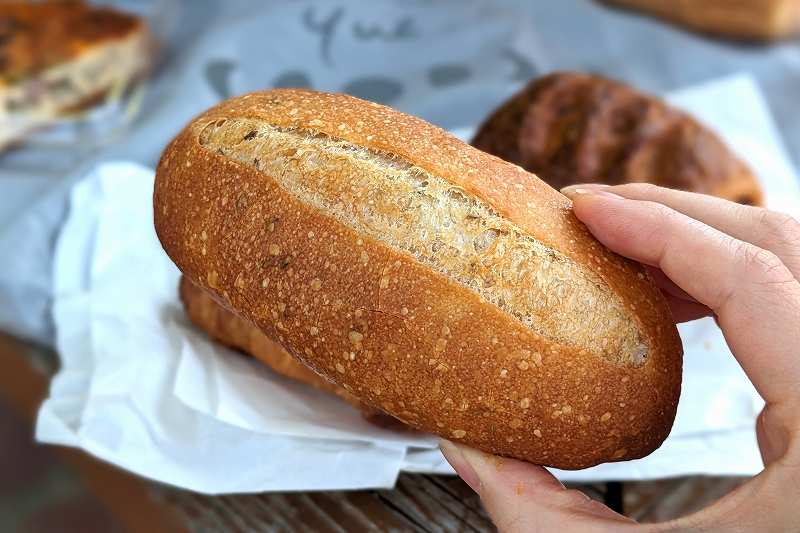 札幌「boulangerie yue.
（ブーランジェリーユエ）」のクミンフランスパンを手に持っている様子